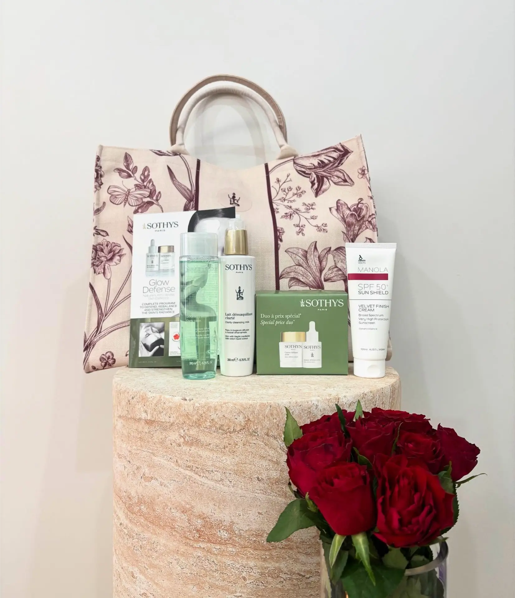 A gift bag of skincare products with fresh roses